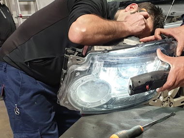 Mechanic inspecting headlight unit from Landrover